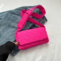 Helle pinke gesteppte Umhängetasche Puffer Bag mit breitem Gurt auf dem Jeansstoff. - Fuchsia