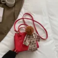 Chic red quilted leather crossbody bag with cute fluffy pompom and plaid scarf detail. - Red