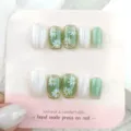 Detalle de uñas postizas hechas a mano con diseño floral de margaritas verdes y brillo. - Paquete de Cartón Tipo Pegamento de Jalea XS