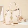 Elegant off-white women handbag with delicate floral embroidery and gold leaf pendant for daily commute. - Azalea - Beige