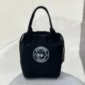 Detailed close-up view of the black canvas drawstring lunch bag, featuring sturdy dual handles. - Black