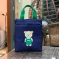 Bolso tote de lona azul oscuro con asas verdes y estampado de oso para uso diario. - Oso de peluche / Azul