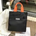 Zwarte canvas lunchtotaas met helderoranje handvatten en voorzak met rits voor dagelijks gebruik. - 0905 Zwart