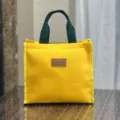 Gele canvas lunchtas met donkergroene handvatten, eenvoudige studenten bento handtas. - Geel label