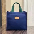 Blauwe canvas lunchtas met groene handvatten en leren label, handige draagtas voor dagelijks. - Blauw met Label