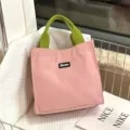 Grote roze lunchtas met groene handvatten, stijlvolle contrasttas voor werk en snacks. - Roze