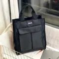 Kοντινό πλάνο μαύρης πολυλειτουργικής τσάντας tote με πρακτικές μπροστινές τσέπες και διπλές λαβές. - Μαύρο