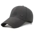 Close-up of dark gray extended brim baseball cap showing textured fabric and metal logo detail. - M Logo / Dark Gray