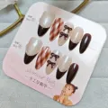 Primer plano detallado de uñas postizas marrones dulces con cuadros, lazos y perlas. - S / Albaricoque Ojo de Gato Cuadrícula Lazo (Paquete de Tarjeta)