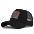 Close-up view of the black trucker hat with brown leather fish patch, mesh back and curved brim. - Adjustable / CM817-1 Black