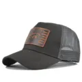 Closeup detail view of dark grey trucker baseball cap with mesh back and brown patch. - Adjustable / Dark Gray