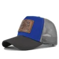 Nahaufnahme der blau-grauen Trucker Cap mit braunem Leder-Patch auf der Vorderseite. - Verstellbar / Dunkelgrau & Blau (Graues Netz)