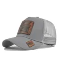 Grijze trucker pet met lederen patch, ademende mesh achterkant en verstelbaar zomerontwerp. - Lichtgrijs