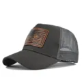 Detailaufnahme der anthrazitfarbenen Trucker Cap mit Tiger-Flaggen-Leder-Patch und Mesh. - Dunkelgrau