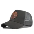 Gorra trucker gris oscuro con parche de cuero marrón redondo y malla trasera transpirable de verano. - Gris oscuro