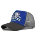 Close-up detail of the mesh trucker cap featuring eagle graphic and Omaha Beach embroidery. - Adjustable / Dark Gray & Blue - Gray Stitching (CP713-24)