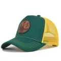 Vista detallada de gorra trucker verde y amarilla con parche de cuero y visera curvada. - Verde y Malla Amarilla
