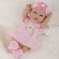Close-up of 11-inch reborn baby doll in pink knitted dress and floral headband on soft fur. - Pink Dress Style (Q11-048-057)