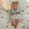 Gros plan détaillé d'une jolie poupée bébé reborn de 20 pouces avec haut vert et bandeau. - Style Haut Vert Et Bretelles (Q20-005-055) / Poupée Reborn 50 cm