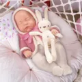Close-up detail of 12-inch cute reborn baby doll in knit clothes with rabbit toy in nest. - Pink Hoodie Set (Closed Eyes) / 12-Inch Doll