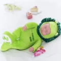 Simulations schlafende Babypuppe im grünen Dinosaurier Plüschkostüm mit süßem Hut und weich. - Schlafender Grüner Löwe
