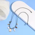 Vista dettagliata della cavigliera intrecciata boho con perle, conchiglie e pendenti. - Lettera A