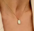 Gedetailleerd overzicht van een delicate gouden halsketting met vierkante letterhanger. - Letter E