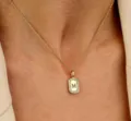Close-up detailopname van een vergulde rechthoekige letter M hanger ketting met zirkonia. - M