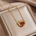 Primo piano dettagliato della collana Claddagh dorata con zircone rosso a cuore. - Collane cuore con corona