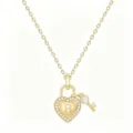 Primo piano del dettaglio della collana con lucchetto a cuore dorato e cristalli brillanti. - Lettera B