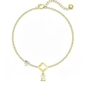 Primo piano dettagliato del ciondolo a trifoglio dorato e del cuore in cristallo sul bracciale. - Lettera B