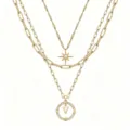 Primo piano della collana multistrato dorata con ciondolo a stella e lettera bussola. - Stile V
