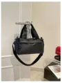 Vista detallada de un bolso cruzado negro de nylon versátil colgado en una puerta con cremallera fuerte. - Negro