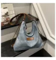 Dettaglio borsa shopper in denim con cinturini in pelle marrone e etichetta frontale. Casual. - Blu