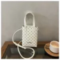 Vista de cerca de un mini bolso de hombro blanco elegante con un diseño de lunares negros. - Blanco