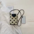 Petit sac bandoulière à pois noirs et blancs avec rabat contrasté et sangle élégante. - Blanc