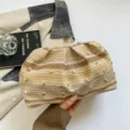 Vista detallada del bolso de mano de paja tejida con tachuelas metálicas y un elegante diseño. - Caqui