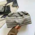 Primer plano detallado del elegante bolso clutch trenzado con tachuelas doradas y pliegues. - Gris
