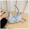 Close-up detail of light blue bow shoulder bag with star pattern and metal logo tag. - Blue