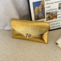 Stylish gold metallic envelope clutch bag featuring a textured pleated design and chic metal clasp. - Gold