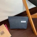 Vista dettagliata della borsa cosmetica in denim, custodia minimalista con etichetta in stoffa. - Blu