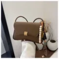 Dettaglio della borsa a tracolla marrone con perline di legno e chiusura metallica curata. - Con Ciondolo / Marrone