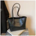 Λεπτομερής όψη μαύρης δερμάτινης τσάντας tote, που δείχνει την υφή της λαβής και την επιφάνεια. - Μαύρο
