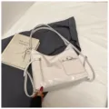 Detail view of the soft leather convertible shoulder backpack, featuring front pocket design. - With Pendant / White