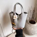 Graue Leder Eimer Tasche für Damen, stilvolle Retro Handtasche mit dekorativem Blumen Anhänger. - Tasche mit Anhänger / Grau