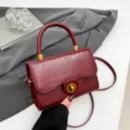 Weinrote strukturierte Henkeltasche mit Drehverschluss und verstellbarem Schulterriemen. - Rot