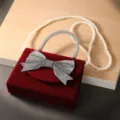 Elegante rode fluwelen avondtas met strass strik en parelketting voor feestelijke jurk. - Parelketing / Bordeauxrood