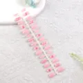 Primer plano detallado de uñas postizas rosa claro con lindos lazos rojos y lunares. - Puntos Rosa Dulce