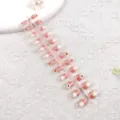 Primer plano de tira de uñas postizas degradadas en rosa con detalles de flores blancas. - Flor Estrella Rosa Transparente