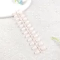 Primer plano detallado de tiras de uñas postizas rosa claro sobre una superficie de exhibición blanca. - Niebla Lechosa Rosa Suave